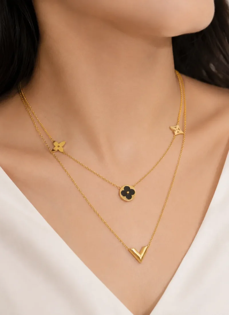 Black Double Layered Charm Necklace featuring layered gold chains with a black floral charm and V-shaped pendant