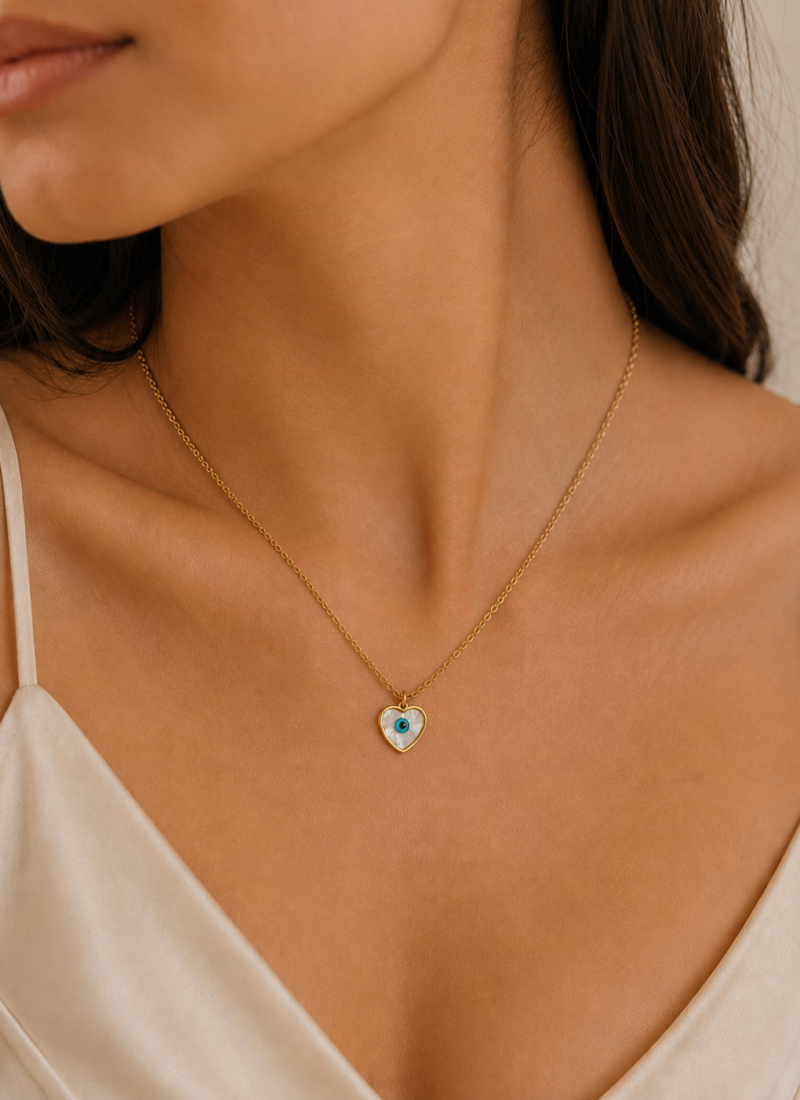 Blue Eye White Heart Necklace featuring a white heart pendant with a blue evil eye centerpiece in a gold finish