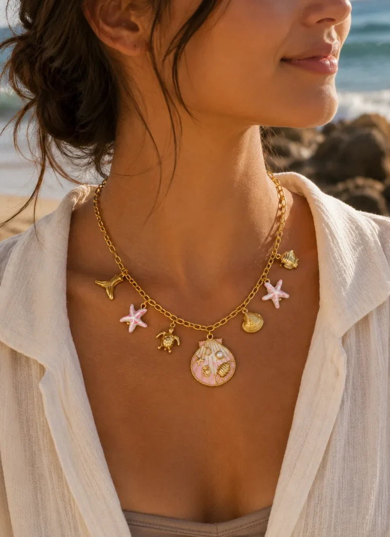 Blush Coastal Charm Necklace featuring a pink shell pendant with starfish, turtle, seashell, and gold beach charms