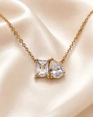 Celeste Twin Stone Necklace featuring emerald-cut and pear-cut clear crystal pendant in a gold setting