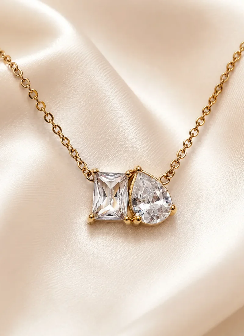 Celeste Twin Stone Necklace featuring emerald-cut and pear-cut clear crystal pendant in a gold setting