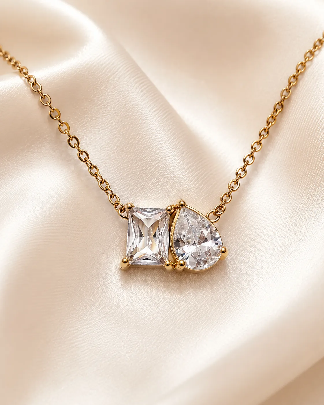 Celeste Twin Stone Necklace Celeste Twin Stone Necklace featuring emerald-cut and pear-cut clear crystal pendant in a gold setting