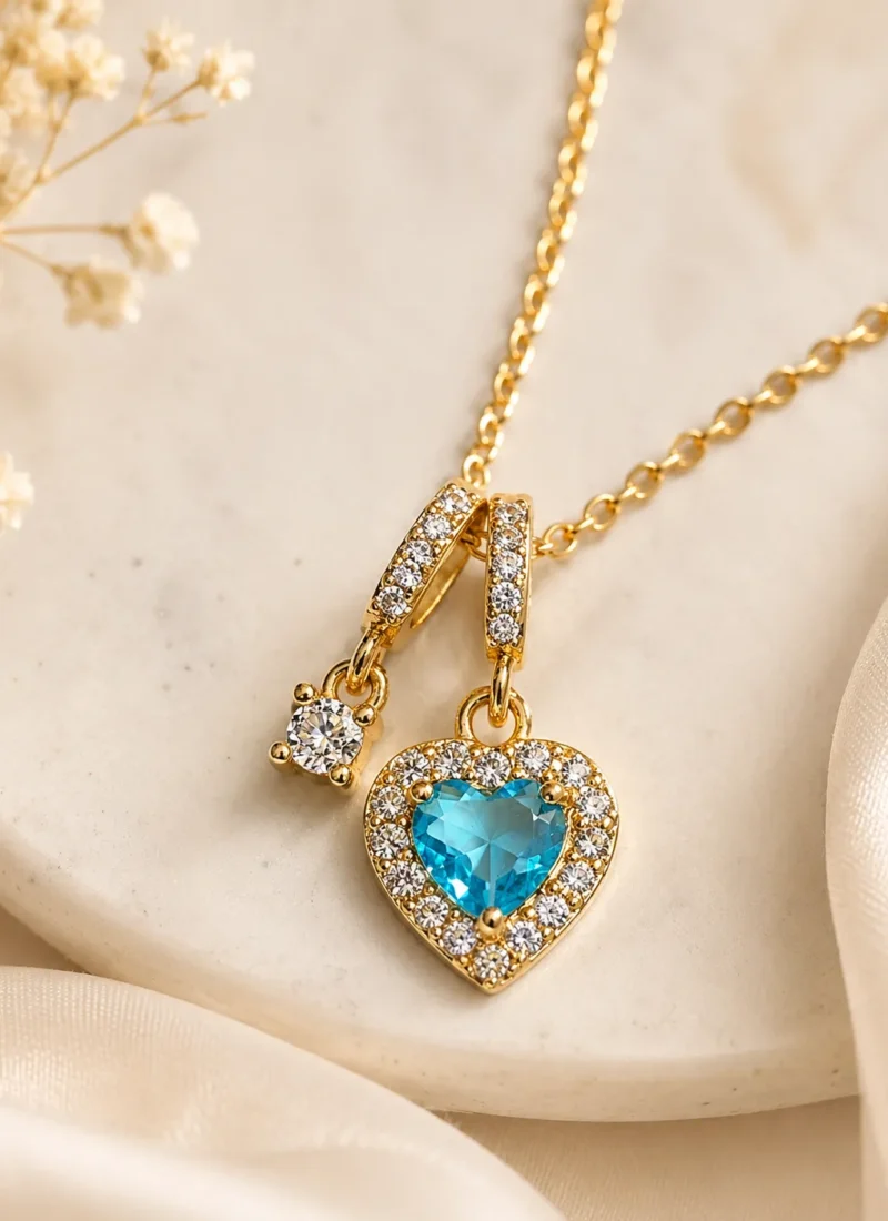 Blue Crystal Heart Pendant Necklace featuring a sparkling blue heart crystal with pavé stones in a premium gold finish