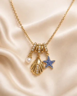 Ocean Blue Starfish Necklace featuring a blue enamel starfish, crystal seashell charm, and pearl pendant in a premium gold finish