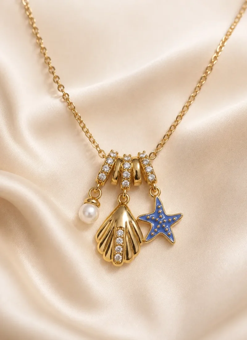 Ocean Blue Starfish Necklace featuring a blue enamel starfish, crystal seashell charm, and pearl pendant in a premium gold finish