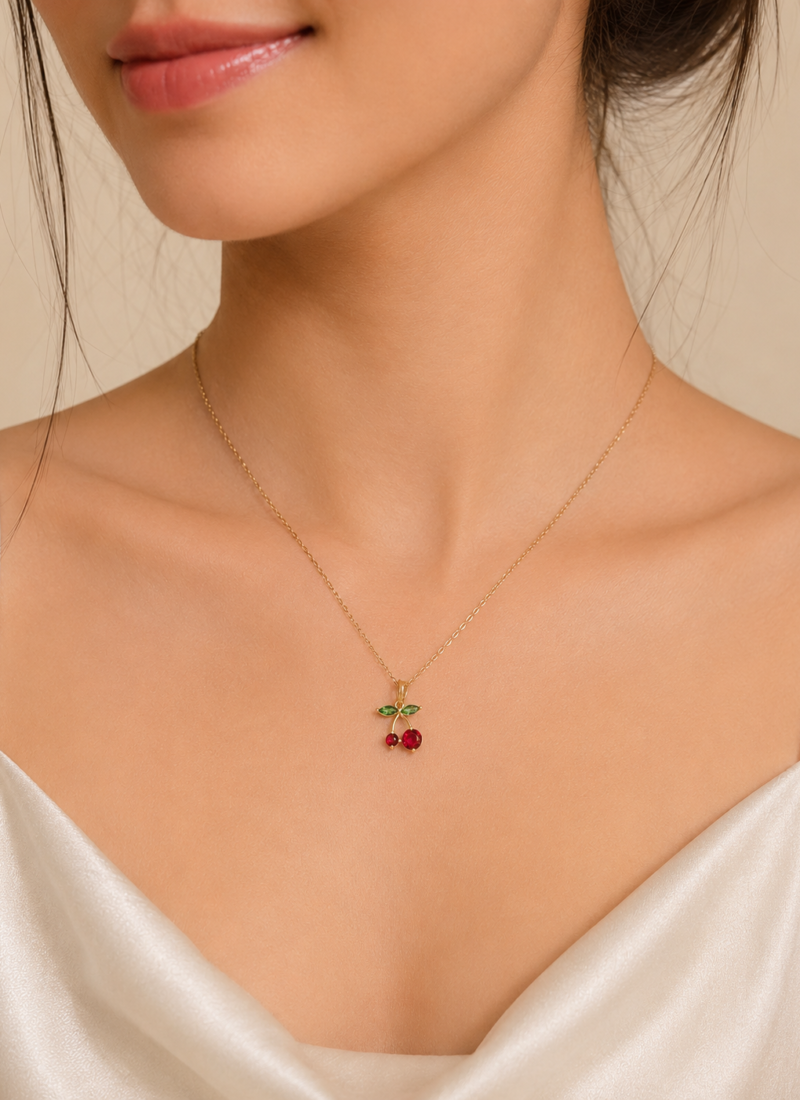 Cherry Blossom Pendant Necklace featuring glossy red cherries and sparkling green crystal leaves in a premium gold finish