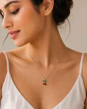 Woman wearing silver cherry pendant necklace with red and green accents